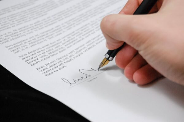 Documento sendo assinado a mão, referente a assinatura da lei 8666.